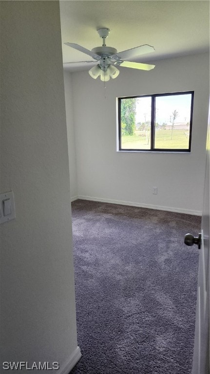 spare room featuring ceiling fan and dark colored carpet