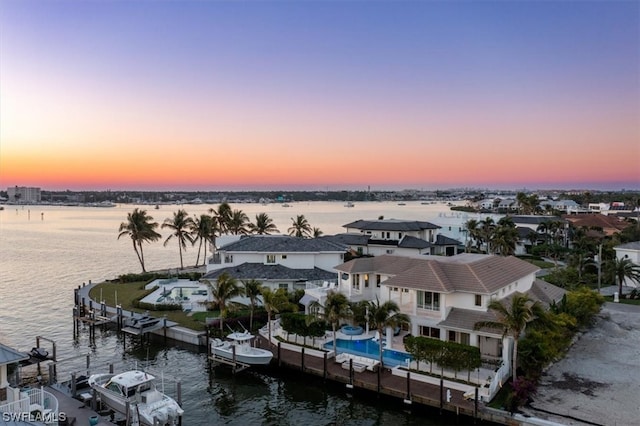 aerial view at dusk featuring a water view