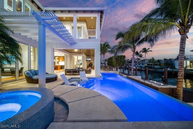 pool at dusk with a pergola, a patio area, an outdoor living space, and a hot tub