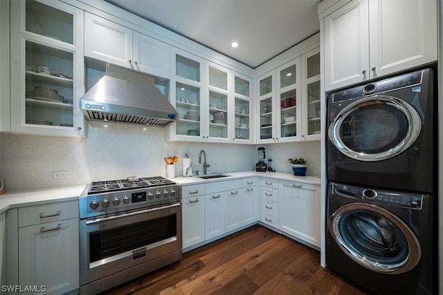 kitchen with sink, stainless steel stove, dark hardwood / wood-style floors, stacked washing maching and dryer, and white cabinetry