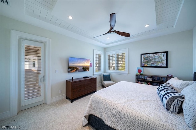 carpeted bedroom featuring a raised ceiling and ceiling fan