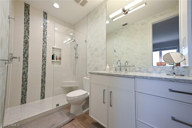 full bathroom featuring vanity, wood finished floors, visible vents, a shower stall, and toilet