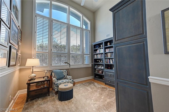 sitting room featuring ceiling fan, visible vents, baseboards, and wood finished floors