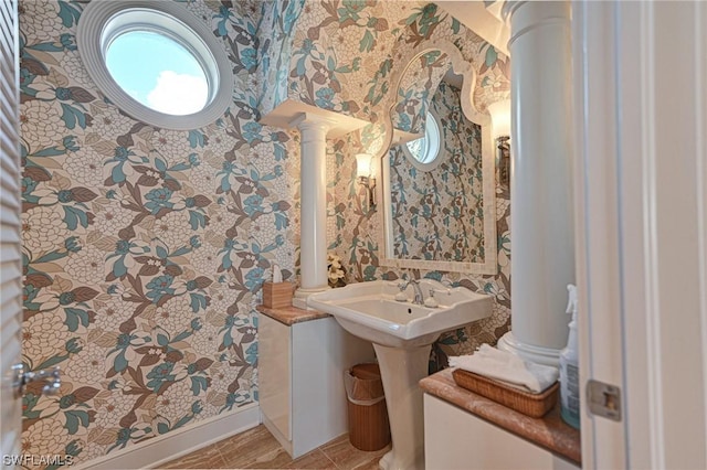 bathroom with wallpapered walls, baseboards, and decorative columns