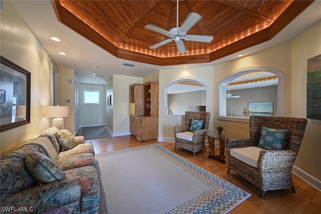 living room featuring wooden ceiling, ceiling fan, and a tray ceiling