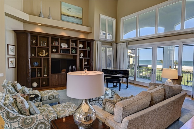 interior space with a water view, light hardwood / wood-style flooring, french doors, and a high ceiling