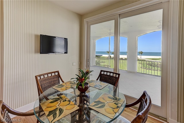 dining room with light hardwood / wood-style floors and a water view