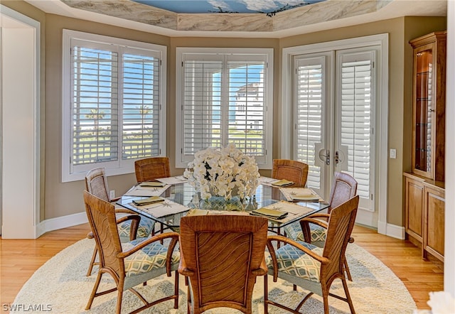 dining space featuring light hardwood / wood-style flooring, a tray ceiling, and plenty of natural light