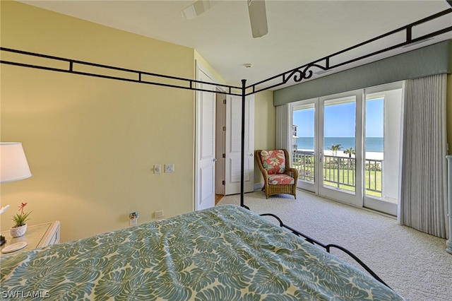 bedroom featuring light colored carpet, ceiling fan, a water view, and access to outside