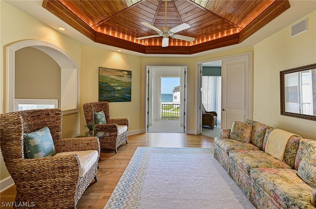 living room with wooden ceiling, light hardwood / wood-style flooring, ceiling fan, and a tray ceiling