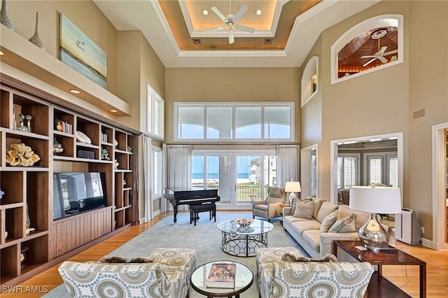 living area with wood finished floors, a ceiling fan, baseboards, and a towering ceiling