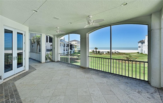 unfurnished sunroom with a water view and ceiling fan