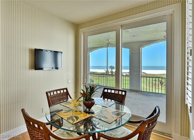 dining room with wallpapered walls, baseboards, and wood finished floors