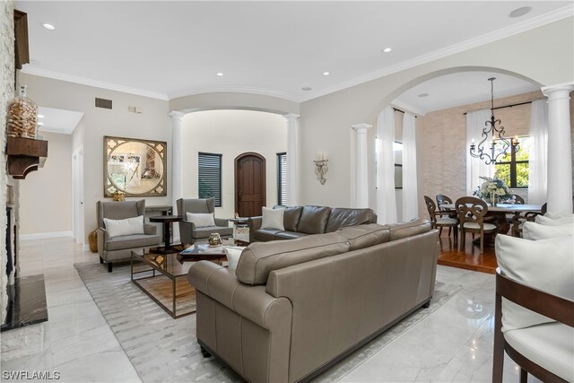 living room featuring decorative columns, crown molding, and a notable chandelier