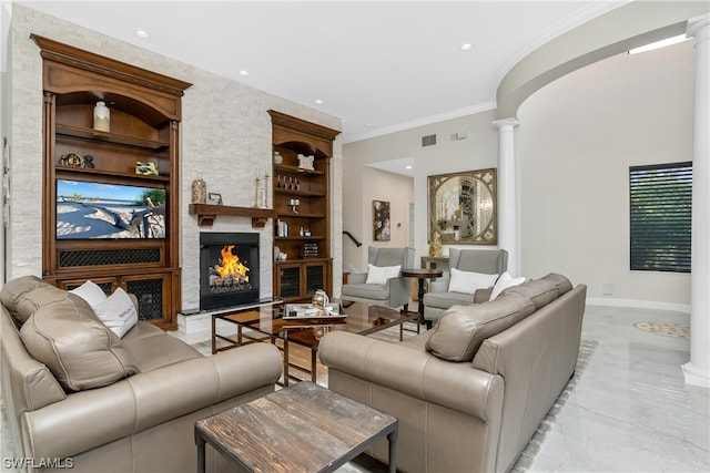 living room featuring built in features, ornamental molding, ornate columns, and a stone fireplace