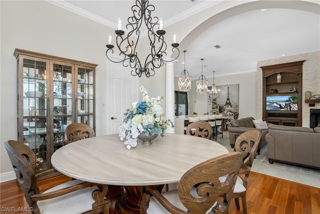 dining space featuring a fireplace, crown molding, and hardwood / wood-style floors