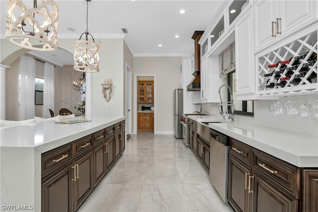 kitchen featuring white cabinets, crown molding, hanging light fixtures, appliances with stainless steel finishes, and dark brown cabinets