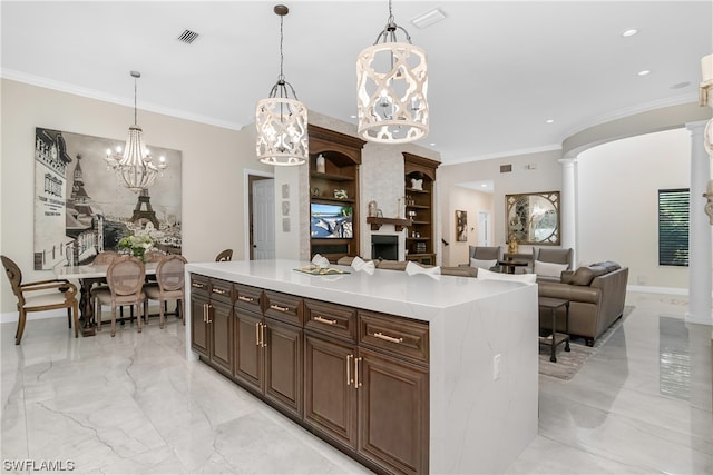 kitchen with ornate columns, a center island, pendant lighting, and ornamental molding