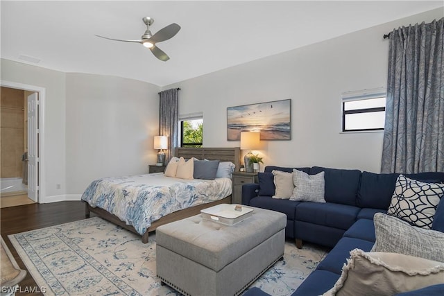 bedroom with multiple windows, hardwood / wood-style floors, ensuite bath, and ceiling fan