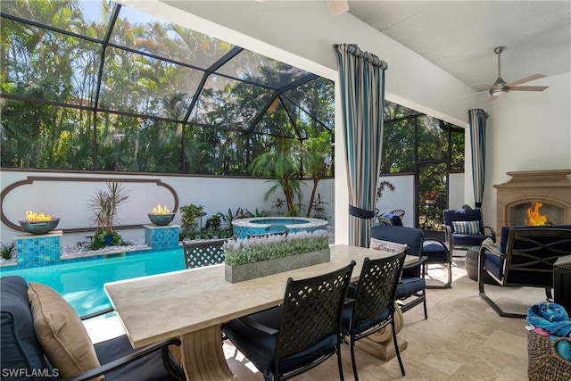 view of patio featuring a lanai, ceiling fan, a fireplace, and a pool with hot tub