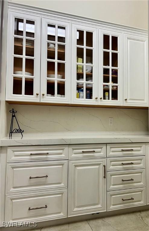 bar featuring light stone counters and white cabinets