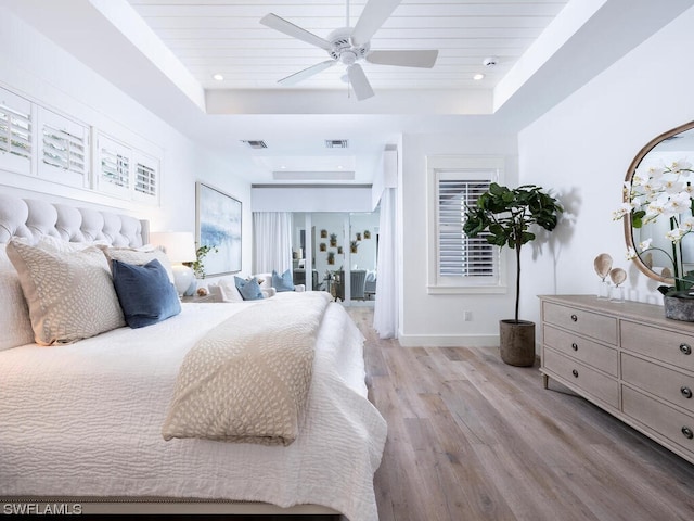 bedroom with a raised ceiling, light hardwood / wood-style floors, and ceiling fan