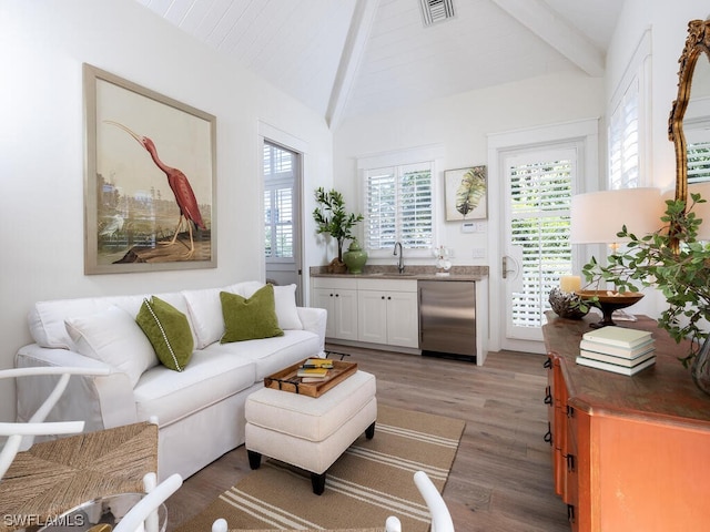 living room featuring sink, wood-type flooring, and lofted ceiling with beams