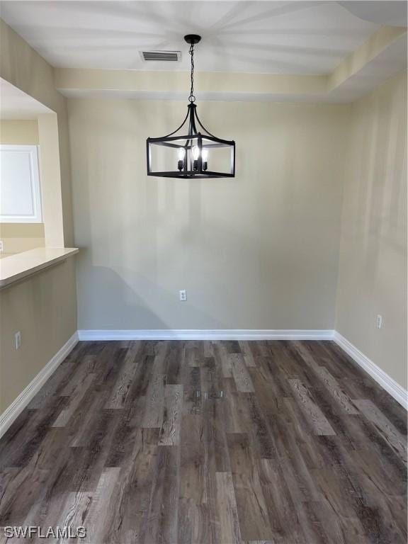 unfurnished dining area featuring an inviting chandelier, visible vents, baseboards, and wood finished floors