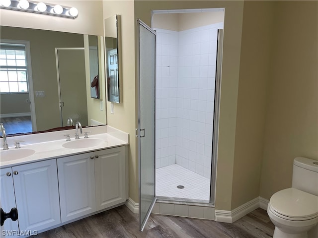 bathroom with toilet, a shower stall, a sink, and wood finished floors