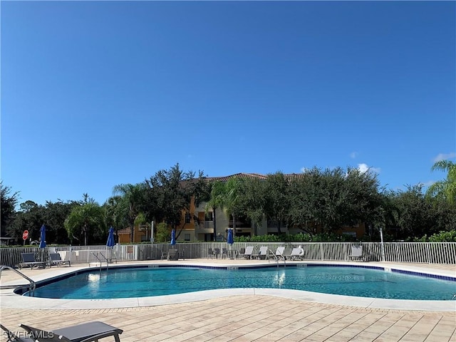 community pool with a patio and fence