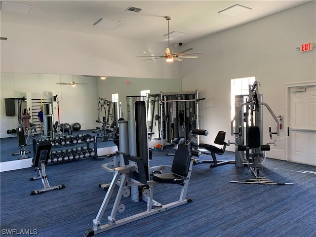 exercise room featuring ceiling fan, a high ceiling, and visible vents