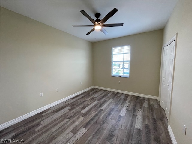 unfurnished bedroom featuring a closet, dark wood finished floors, and baseboards