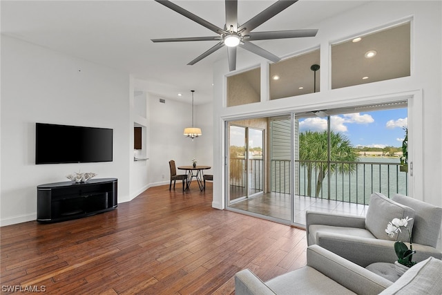 living room with dark hardwood / wood-style floors, a healthy amount of sunlight, ceiling fan, and a high ceiling