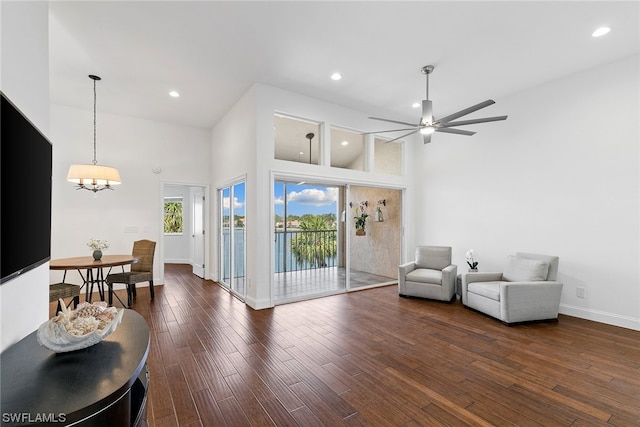 living room with ceiling fan with notable chandelier, high vaulted ceiling, and dark hardwood / wood-style flooring