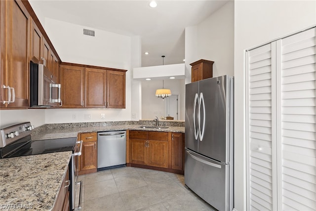 kitchen with stainless steel appliances, decorative light fixtures, light stone countertops, and sink