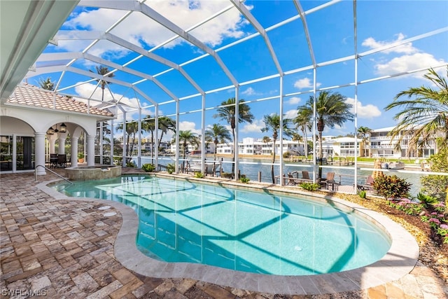 view of swimming pool with glass enclosure, a patio area, and a water view