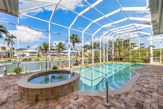 view of swimming pool with glass enclosure, an in ground hot tub, a patio area, and a water view