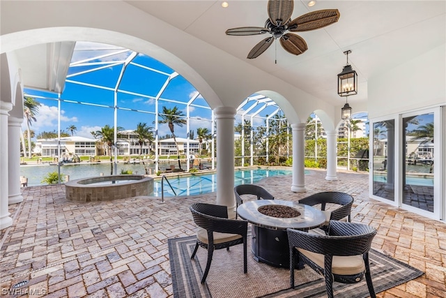 view of patio featuring glass enclosure, ceiling fan, a water view, and a pool with hot tub