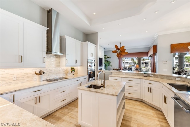 kitchen featuring white cabinets, stainless steel appliances, wall chimney exhaust hood, and light hardwood / wood-style floors