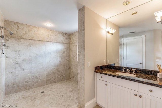 bathroom with a tile shower and vanity