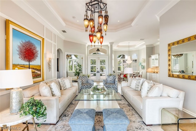 living room with french doors, a raised ceiling, crown molding, light wood-type flooring, and a notable chandelier