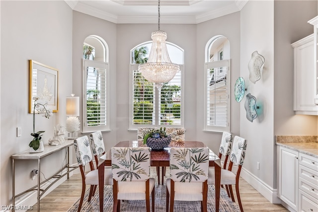 dining area with light wood-type flooring, crown molding, and a notable chandelier