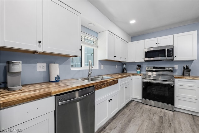 kitchen featuring sink, light hardwood / wood-style flooring, stainless steel appliances, butcher block counters, and white cabinetry