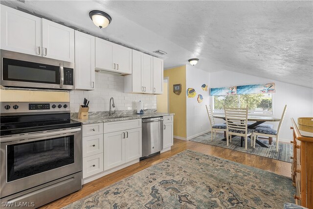 kitchen featuring appliances with stainless steel finishes, white cabinetry, and light wood-type flooring