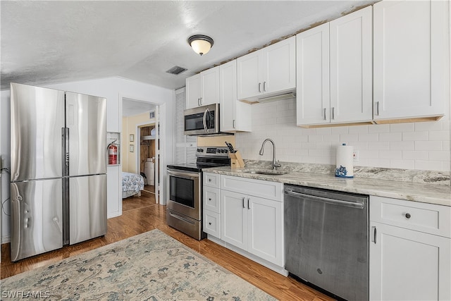 kitchen with white cabinets, appliances with stainless steel finishes, dark hardwood / wood-style floors, and sink