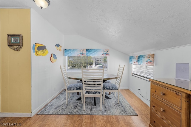 dining room featuring lofted ceiling, a textured ceiling, light hardwood / wood-style floors, and a healthy amount of sunlight