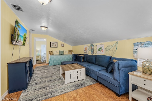 living room featuring lofted ceiling, a textured ceiling, and light hardwood / wood-style flooring