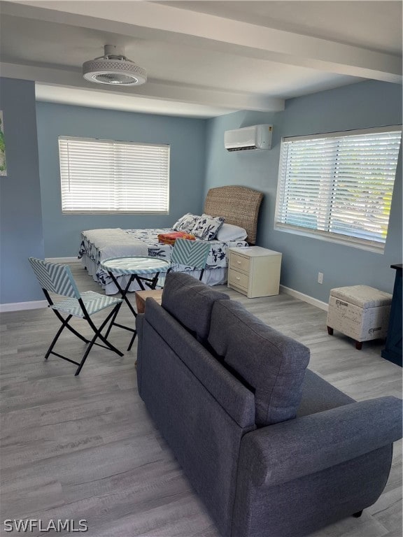 interior space with beamed ceiling, a wall unit AC, and light wood-type flooring