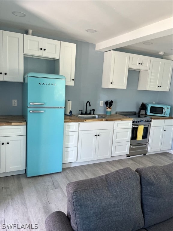 kitchen with light hardwood / wood-style floors, white appliances, and white cabinetry