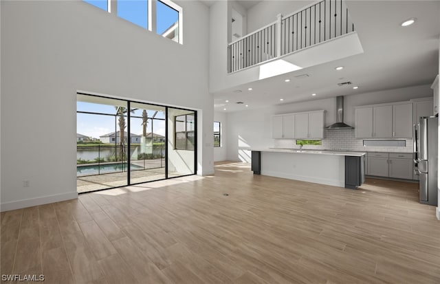 unfurnished living room featuring a high ceiling, light wood-type flooring, and a wealth of natural light